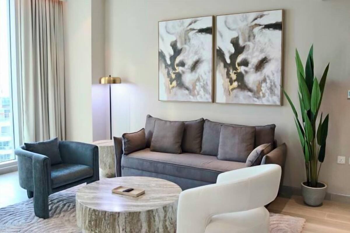 A modern living room with a grey sofa, a round coffee table, and a large potted plant.