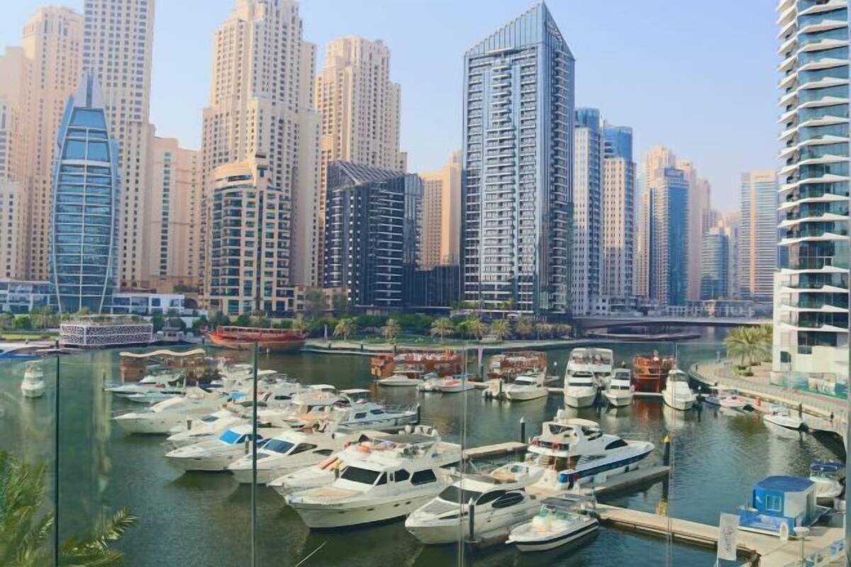 A marina with multiple yachts docked, surrounded by high-rise buildings.