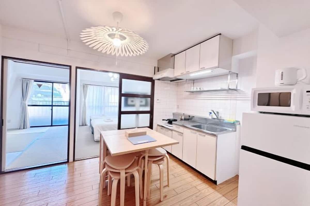 A modern kitchen with white cabinets, a wooden dining table, and a unique ceiling light fixture.