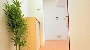 A hallway with a bamboo plant, a wooden floor, and a white wall. - City Heim Building (Tokyo)