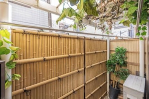 A bamboo fence with a vertical slat design, a potted plant, and a small structure on the right. - daiwa Hotel, Skytree, Ueno Park, Asakusa Temple (Tokyo)