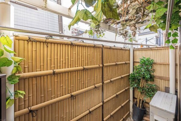 A bamboo fence with a vertical slat design, a potted plant, and a small structure on the right. - daiwa Hotel, Skytree, Ueno Park, Asakusa Temple (Tokyo)