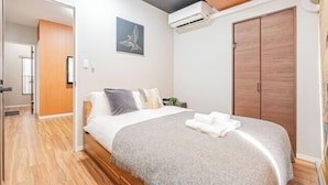 Una camera da letto con un letto, un armadio in legno e un condizionatore d'aria a parete.