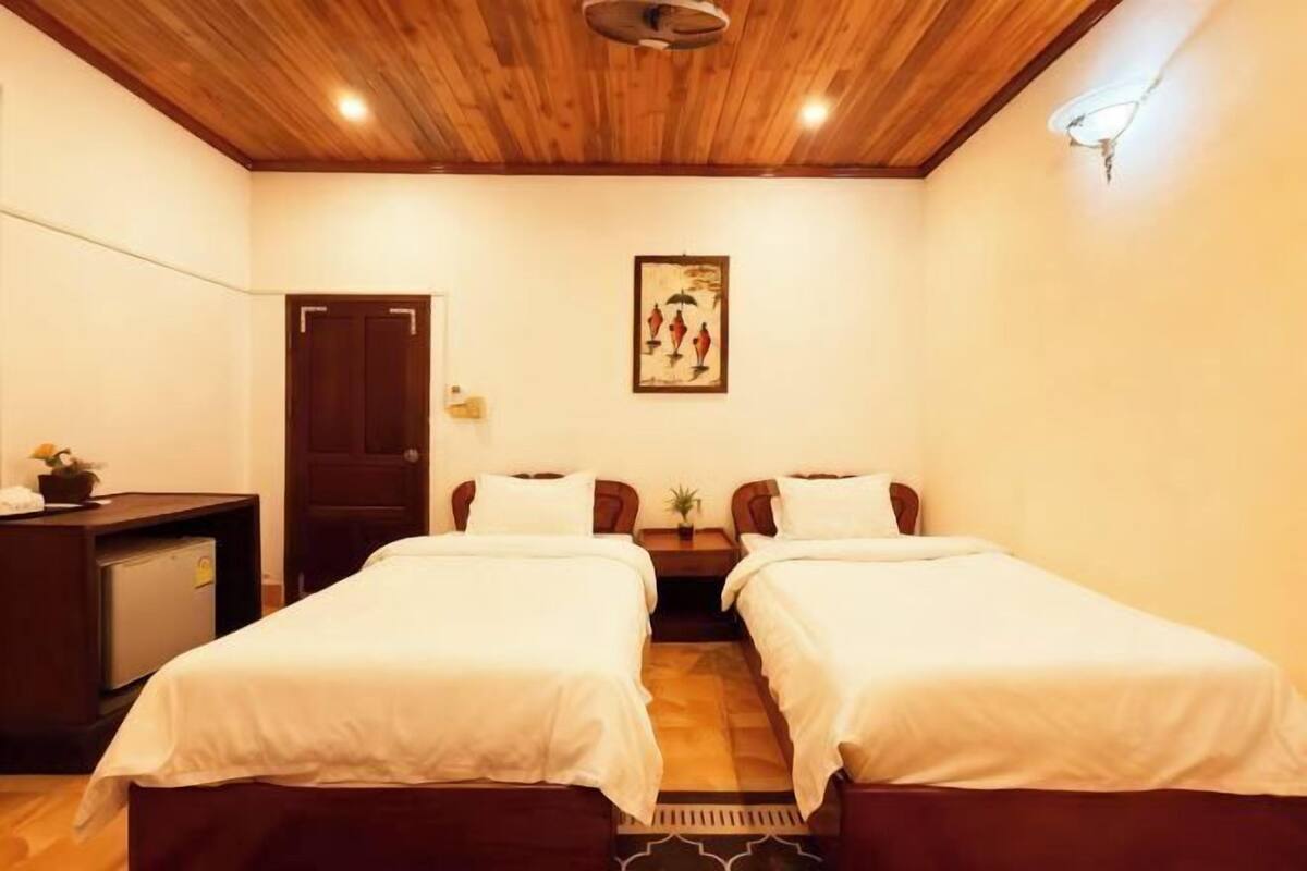 A room with two beds, a desk, a door, and a painting on the wall.