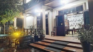 A building with a covered outdoor area, potted plants, and a table with chairs. - Nan Ya Hotel(Sene Hua Phanh Guesthouse) (Luang Prabang)