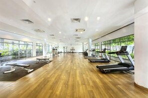 Une salle de sport spacieuse équipée de tapis de course, d’appareils de musculation et dotée d’un plancher en bois.