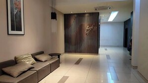 A modern lobby with a sofa, a vertical wooden panel, and a framed artwork on the wall.