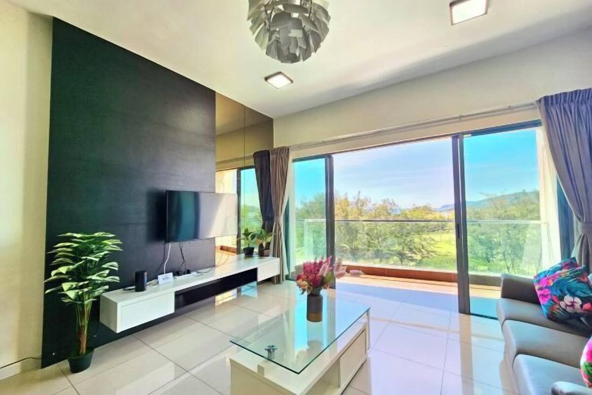 A modern living room with a flat-screen TV, a glass coffee table, a sofa, and a balcony with a view.
