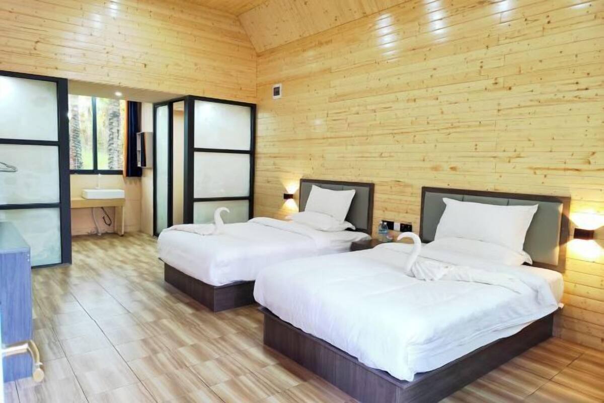 A wooden-paneled room with two beds, a sink, and a small desk.