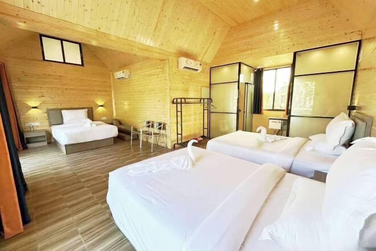 A wooden cabin room with two beds, a small table, and a chair.