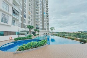 A swimming pool with a view of a high-rise building, surrounded by greenery. - Malaysia Kulai D'Putra Suites Serviced Apartment (Kulai)