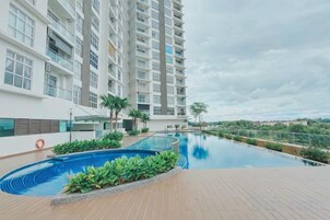 Un moderno edificio de apartamentos con piscina en la azotea y vistas del paisaje circundante.