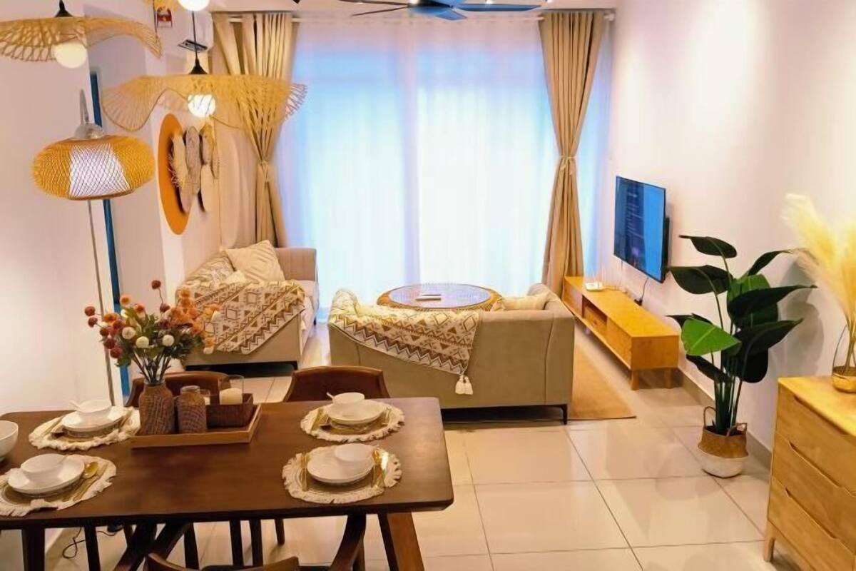 Ein modernes Wohnzimmer mit einer Couch, einem Esstisch gedeckt mit Tellern, einem an der Wand montierten Fernseher und einem Deckenventilator.