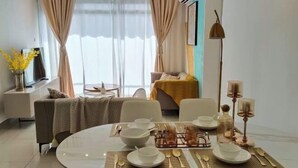 Un comedor moderno con una mesa redonda para cuatro personas, un sofá, un televisor y una cama al fondo.