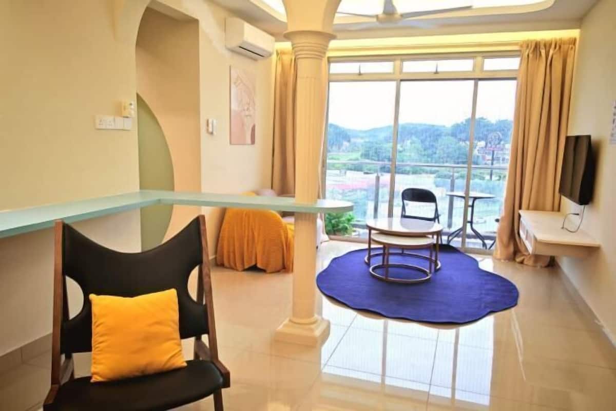 Ein Hotelzimmer mit Balkon, Esstisch, Fernseher und Blick ins Freie.