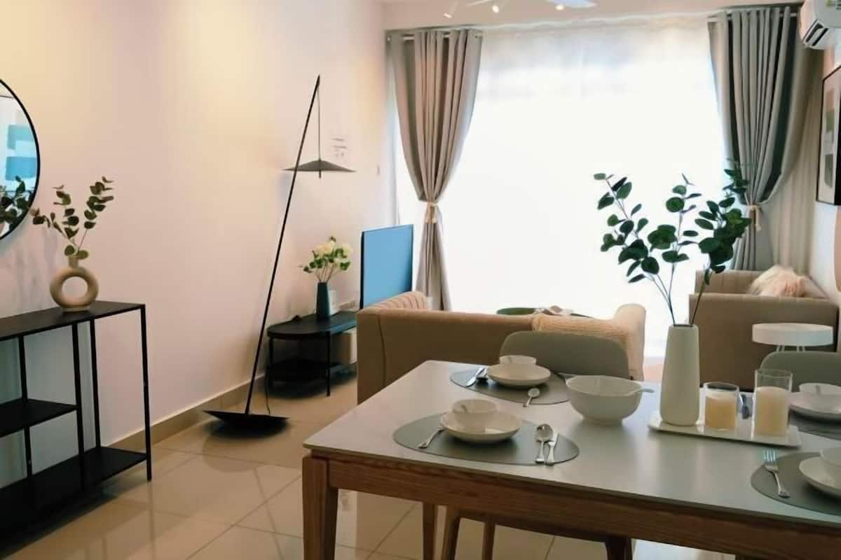 Ein modernes Wohnzimmer mit Esstisch für zwei Personen, einer Couch, einem Couchtisch und einer Stehlampe.