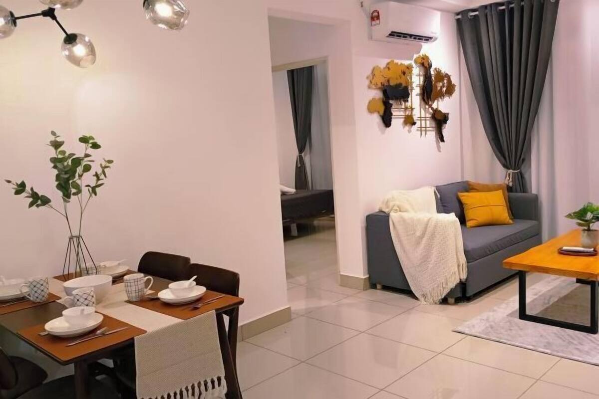 Ein modernes Wohnzimmer mit einem Esstisch für zwei Personen, einer Couch mit Decke und einem Couchtisch.