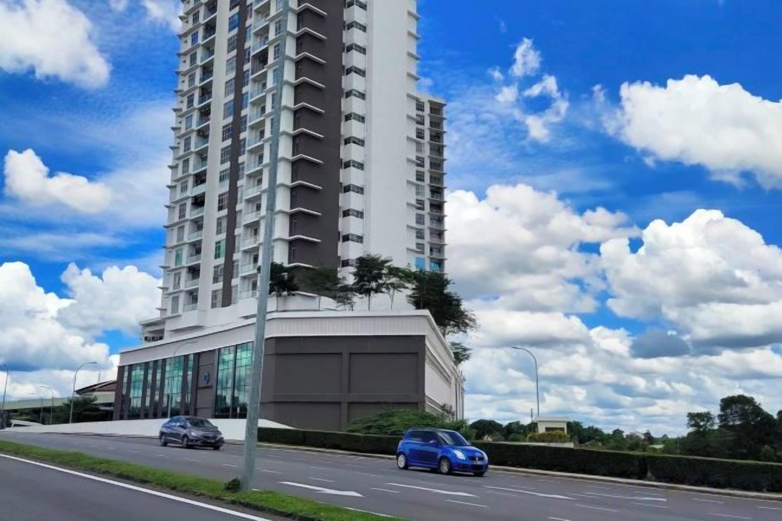 A tall residential building with a modern design, featuring a large glass facade and a flat roof.
