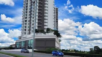 A tall residential building with a modern design, featuring a large glass facade and a flat roof.