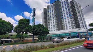 Un edificio alto con varios pisos, rodeado de vegetación y un cielo despejado.