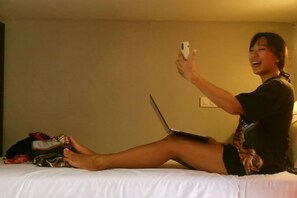 Iemand zit op een bed met een laptop en een smartphone.