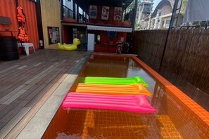 A swimming pool with inflatable toys and a wooden deck. - U Box Hostel (Koh Samui)