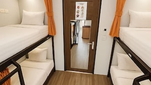 Una stanza con due letti, una porta in legno e un angolo cottura.