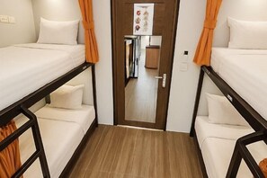 Una habitación con dos camas, una puerta de madera y una pequeña cocina.