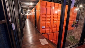 Un corridoio con pavimento in legno, ringhiere in metallo e container arancioni.