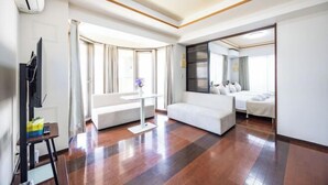 Una habitación de hotel moderna con sofá, cama, televisor y escritorio con silla.