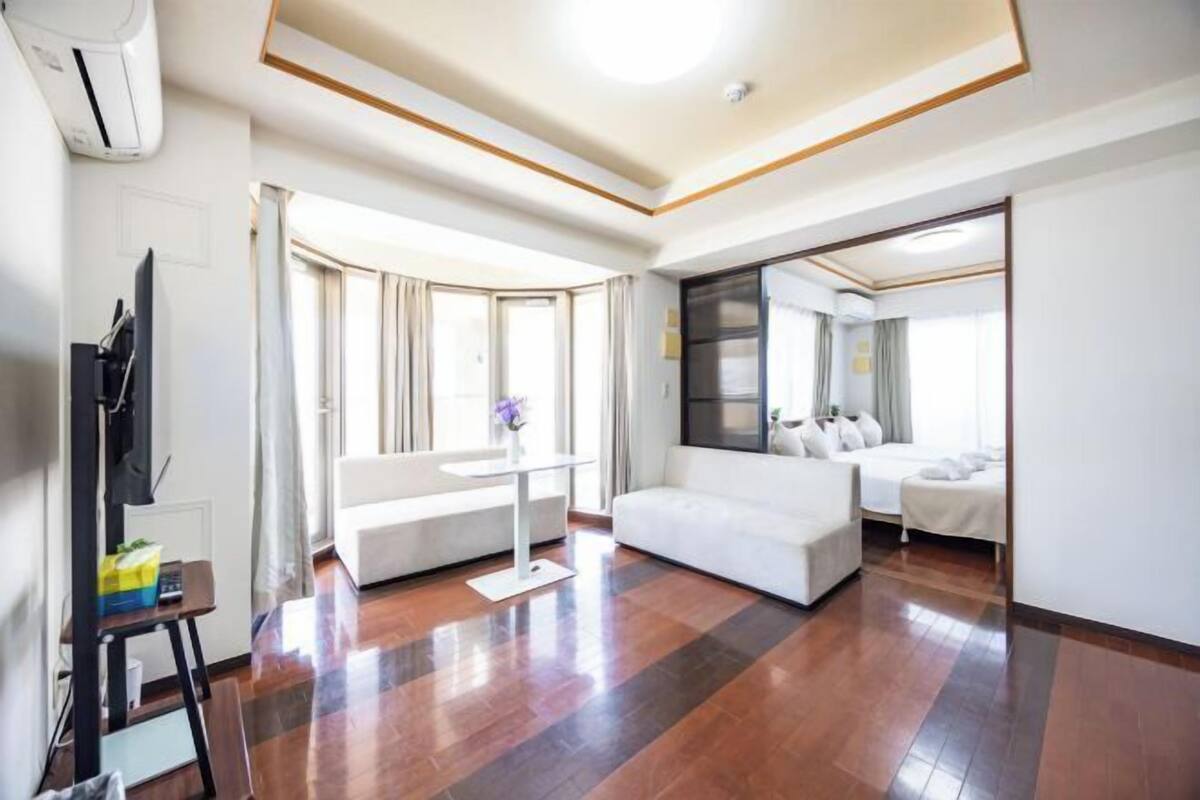 Quarto de hotel moderno com sofá, cama, televisão e secretária com cadeira.