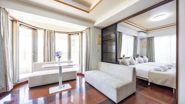 Habitación de hotel con sofá, cama, un espejo grande y una ventana con cortinas.