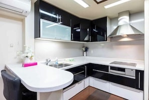 A modern kitchen with black and white cabinetry, a white countertop, and a stainless steel range hood.