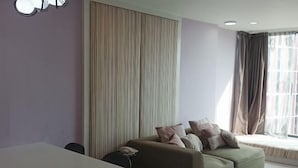 Ein modernes Wohnzimmer mit einer Couch, einem Esstisch und einem großen Fenster mit Vorhängen.