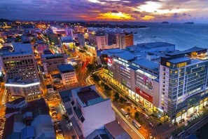 A cityscape with buildings, roads, and a body of water during twilight.