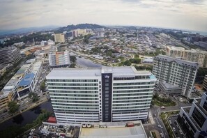 A multi-story hotel with a prominent 'Sky' sign, surrounded by other buildings and a river. - Urban Retreat @ KK Sky • Pool • Parking (Kota Kinabalu)