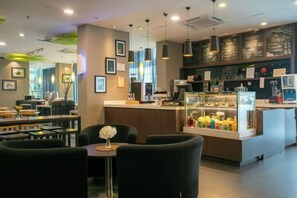 A modern cafe with a bar area, seating arrangements, and a counter with a display case.