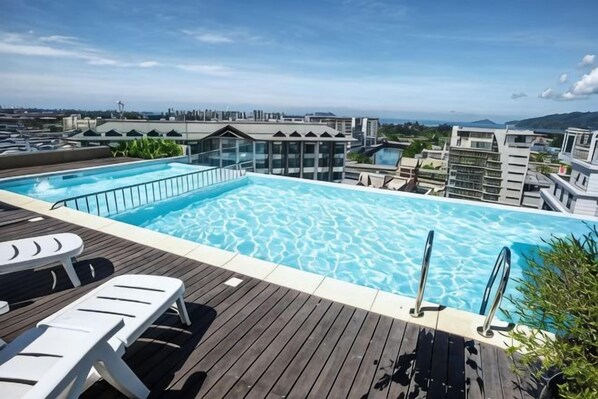 A rooftop swimming pool with a view of the cityscape.