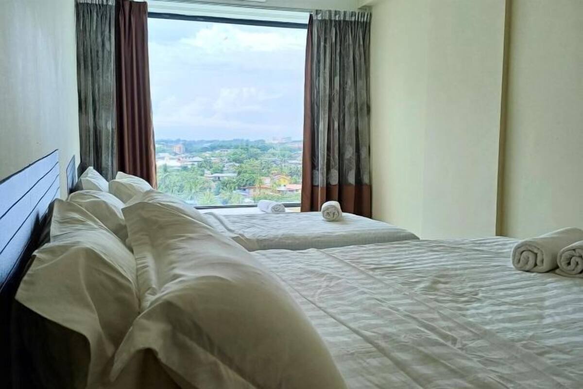 A hotel room with two beds, a view of a cityscape, and curtains.