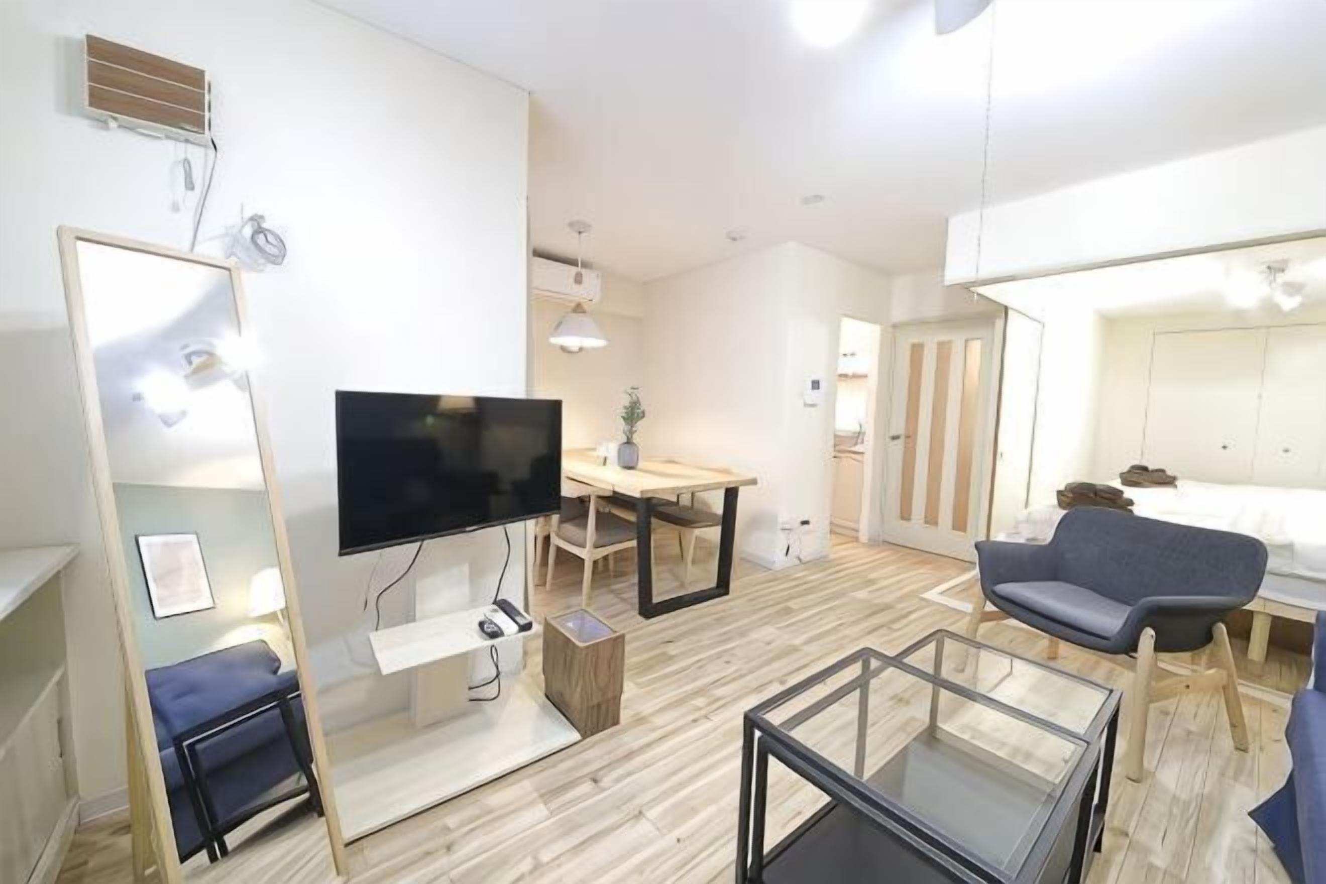 Una habitación de hotel moderna con televisión de pantalla plana, una mesa de comedor, un sofá y una cama.
