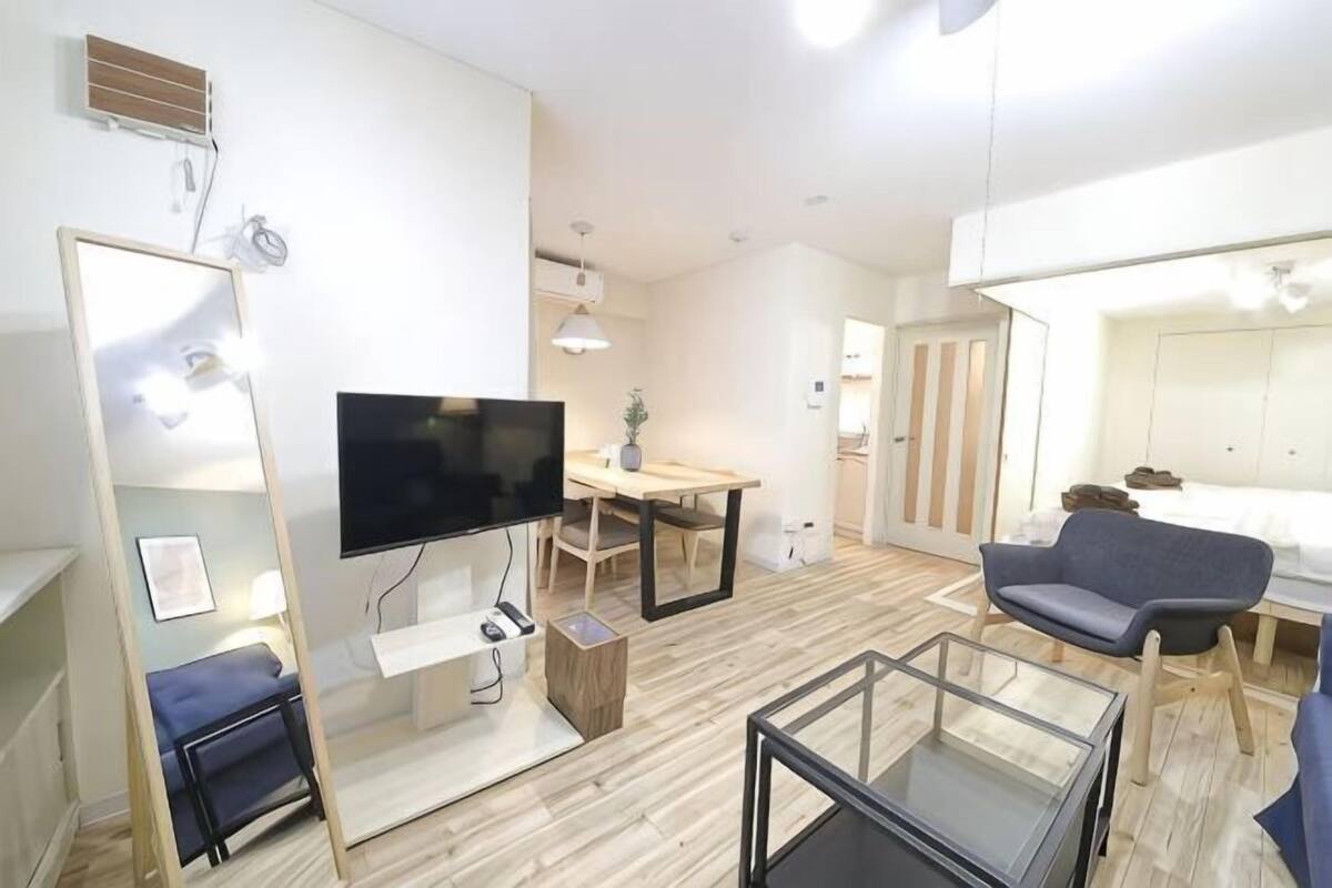 A modern hotel room with a flat-screen TV, a dining table, a sofa, and a bed.