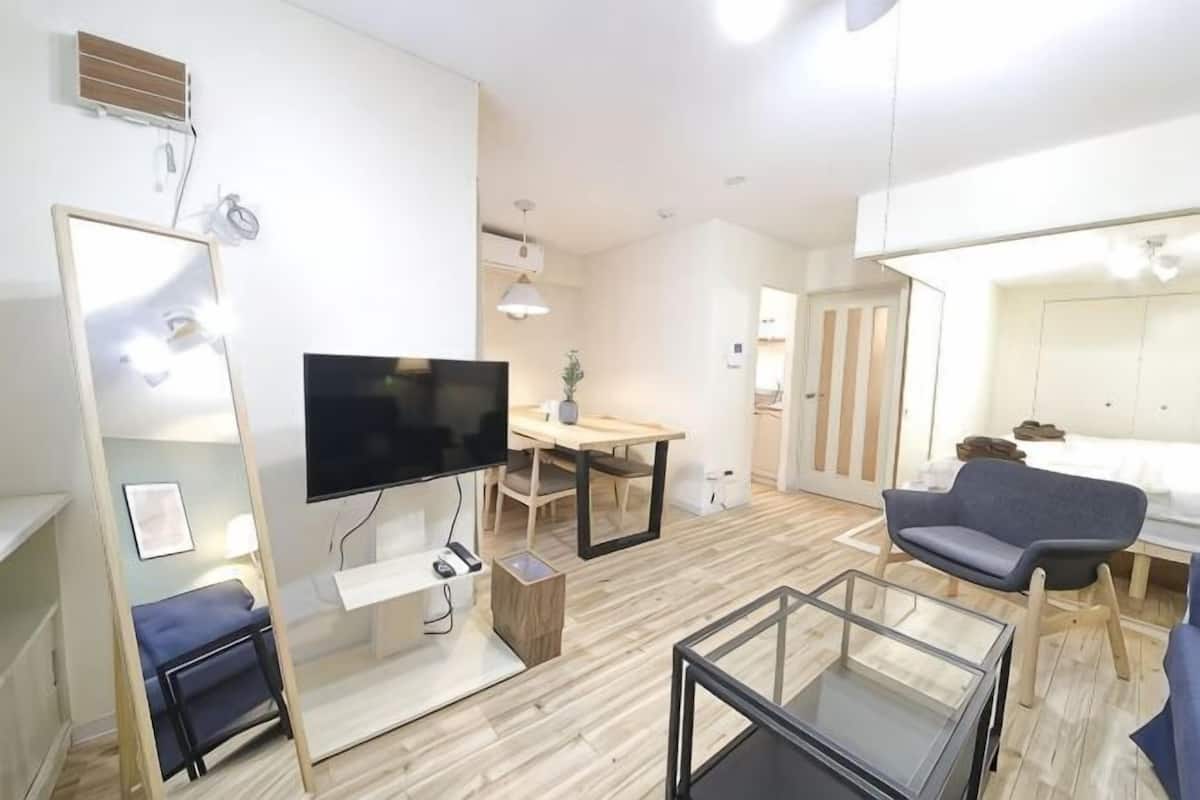 Una habitación de hotel moderna con televisión de pantalla plana, una mesa de comedor, un sofá y una cama.