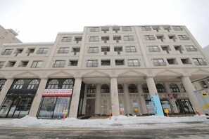 A multi-story building with a symmetrical facade, large windows, and a central entrance with columns. - Northern Hills Minami 6 (Sapporo)