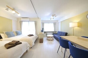 Habitación de hotel con dos camas, una mesa de comedor, sillas, una mesita redonda y un sofá.