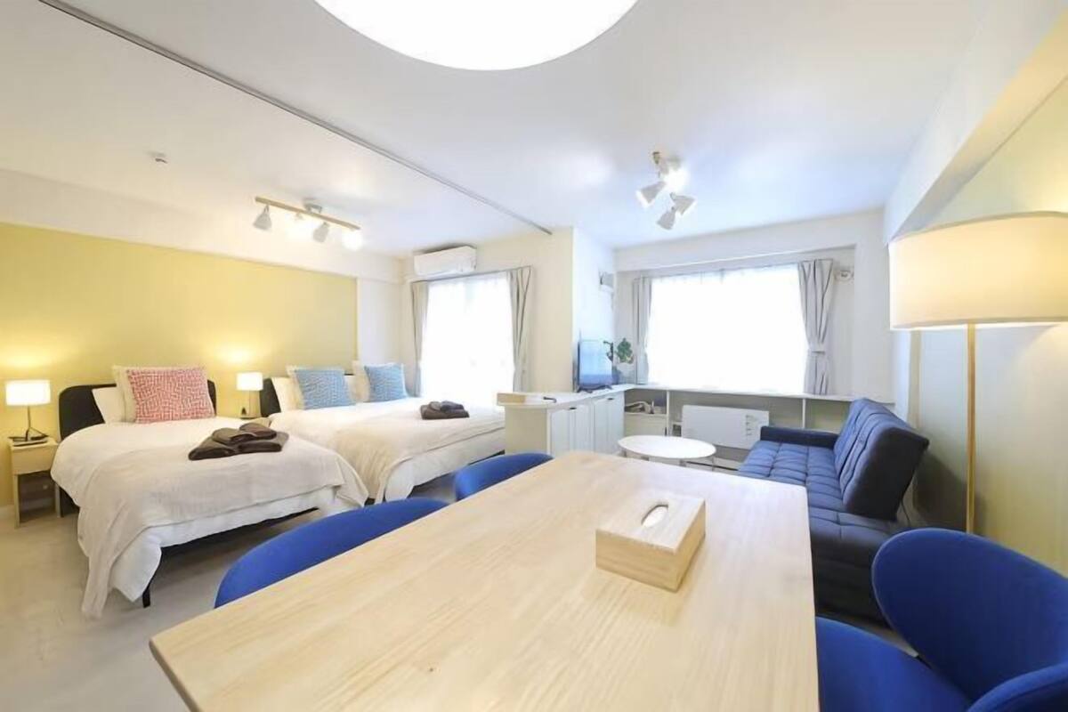 A hotel room with two beds, a dining table, a sofa, and a TV.