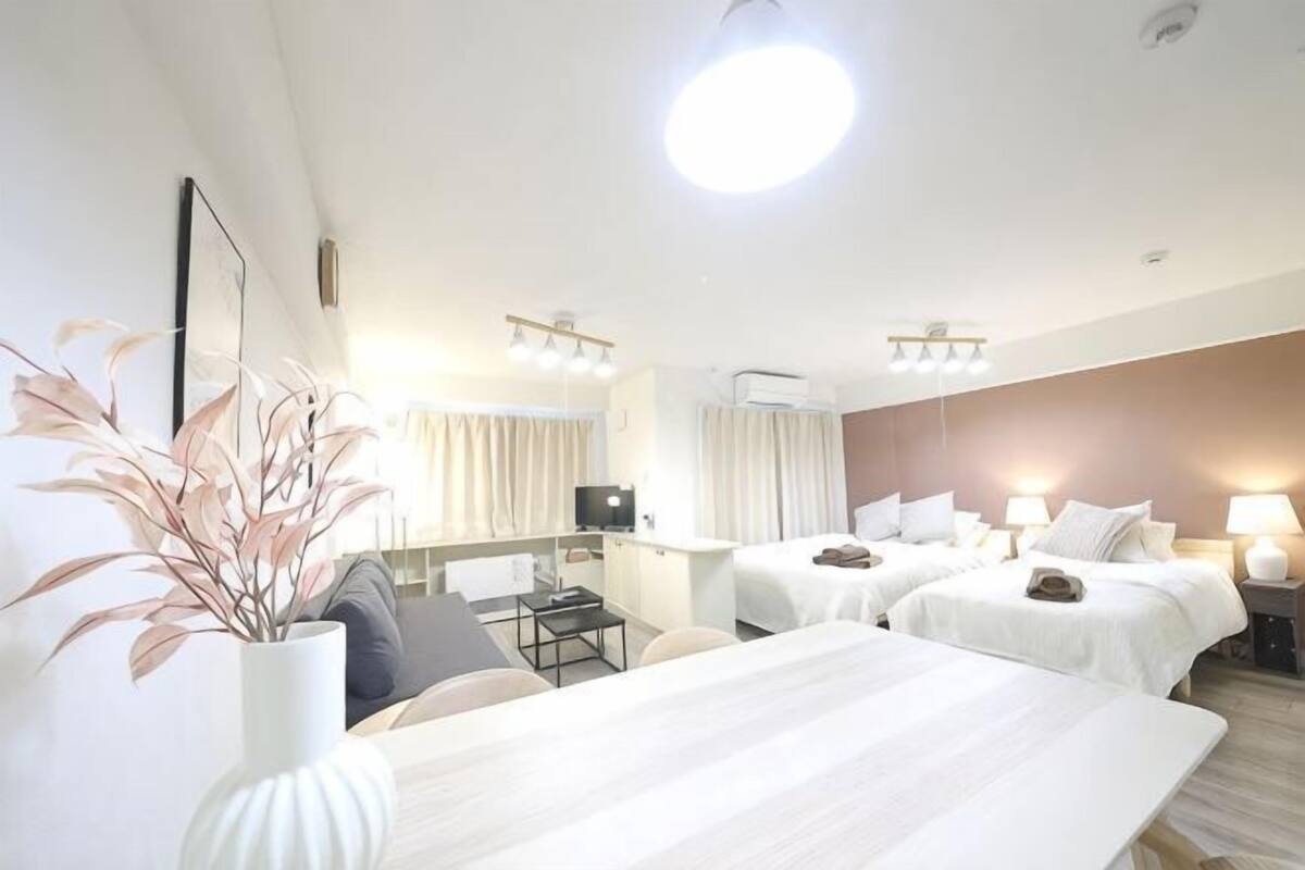 A hotel room with a bed, bedside tables, a desk, a chair, a TV, and a plant.
