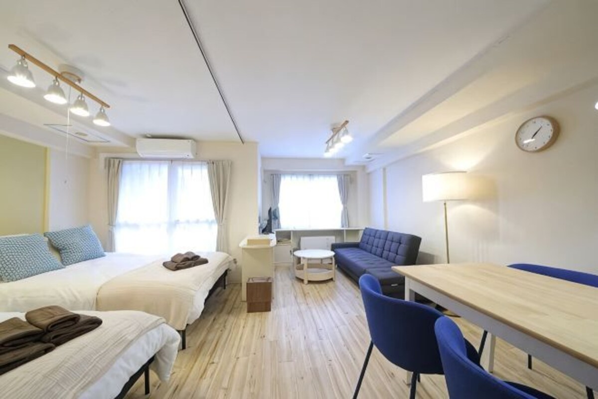 Una habitación de hotel compacta con dos camas, un sofá, una mesa de comedor y un pequeño rincón de estar.