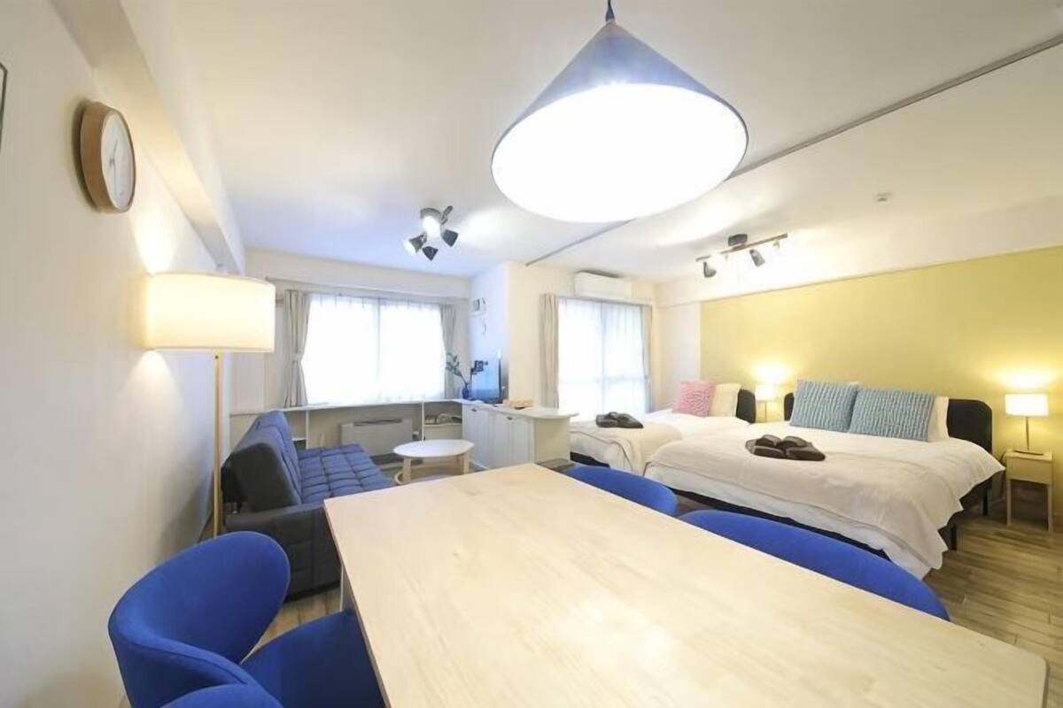 A hotel room with a bed, a desk, a chair, a lamp, and a window.
