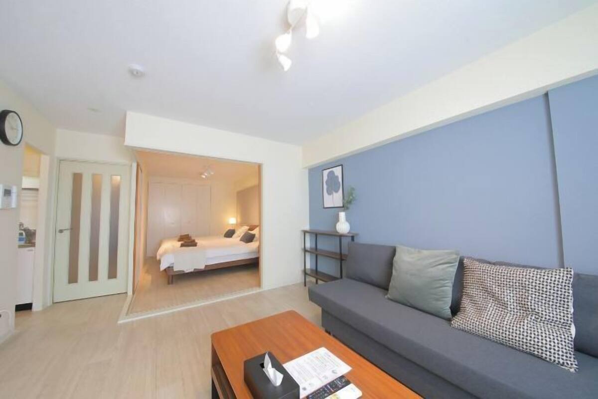 A modern hotel room with a sofa, a coffee table, a bed, and a door leading to another room.