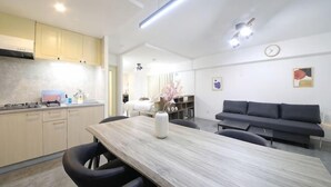A modern kitchen with a dining area, a sofa, and a clock on the wall. - Northern Hills Minami 6 (Sapporo)